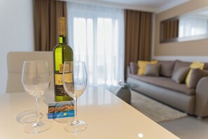 A hotel room with a dining table, two wine glasses, a wine bottle, and a brochure.