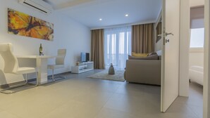 Un saló modern amb un sofà, una taula de dinar amb cadires, una televisió i un quadre a la paret.