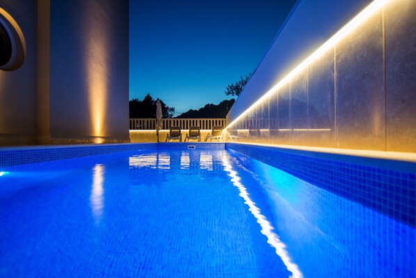 A swimming pool with a clear view of the surrounding area, including a building and trees.