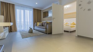 Habitació d'hotel moderna amb sofà, llit, escriptori i una finestra gran amb cortines.