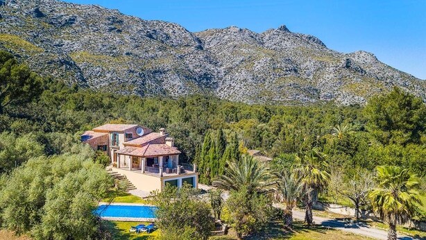 A villa with a pool, surrounded by trees and mountains.