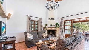 A cozy living room with a fireplace, a television, and a dining area with outdoor seating.