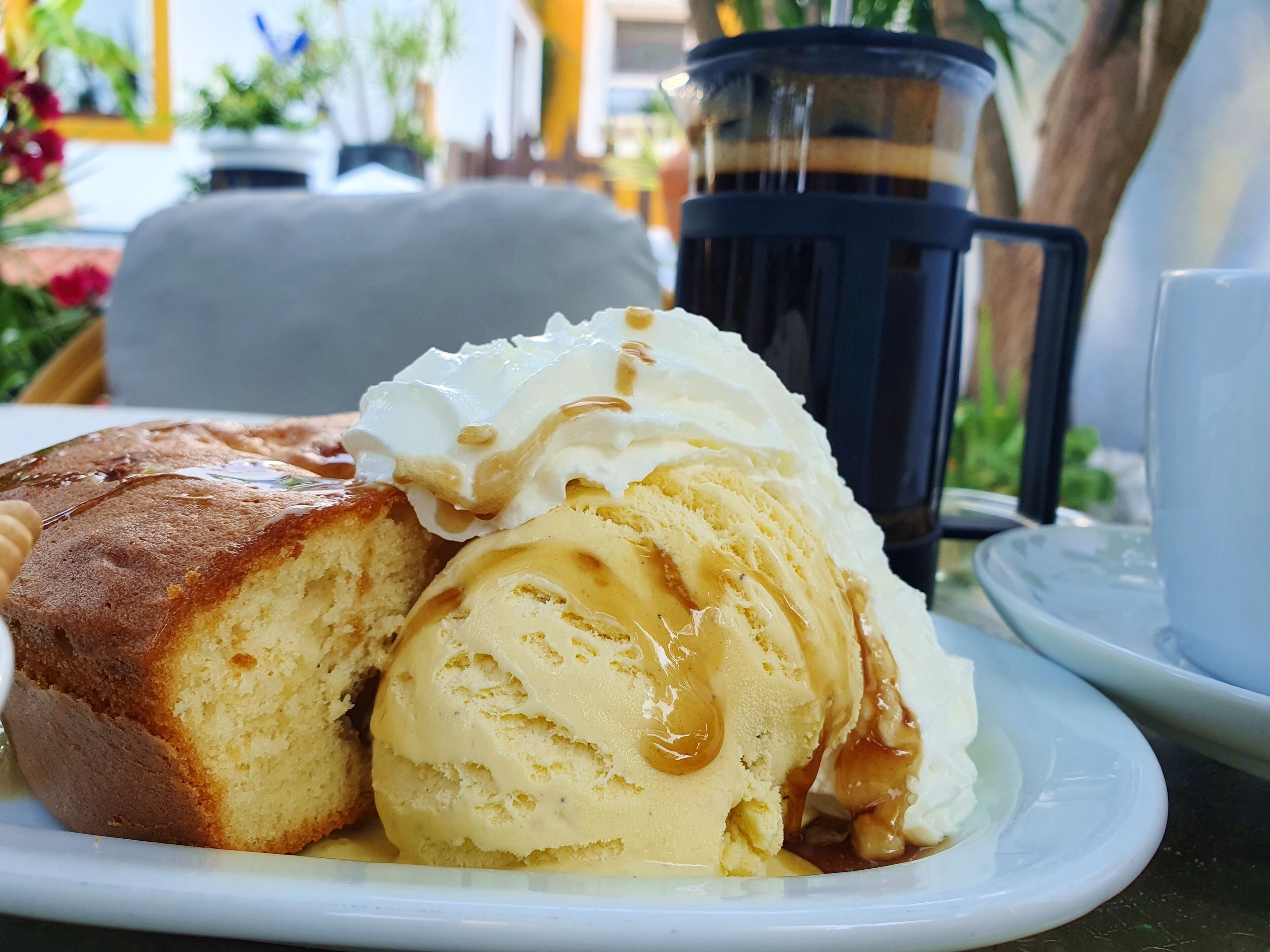 Une assiette avec une part de gâteau et une boule de glace à la vanille, le tout nappé de sauce au caramel.