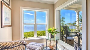 A room with a large window overlooking a scenic view, a small table with a plant, and a cozy seating area. - 3 bedroom 2 bath Ocean front condo on marina with opt boat slip.   (Key West)