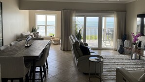 A spacious living area with a dining table, sofa, and a balcony with a view of the sea. - 3 bedroom 2 bath Ocean front condo on marina with opt boat slip.   (Key West)