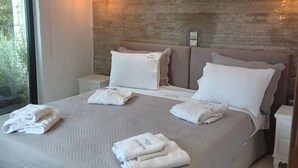 A modern bedroom with a large bed, two bedside tables, a wall-mounted air conditioner, and a large window. - Villa Elizabeth with pool close to Fiskardo (Fiskardo)