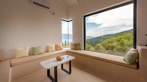A modern living room with a large window offering a scenic view of a hilly landscape. - Villa Elizabeth with pool close to Fiskardo (Fiskardo)