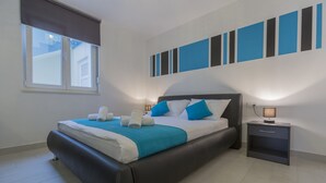 Un dormitorio moderno con una cama grande, una mesita de noche y una ventana con persianas.