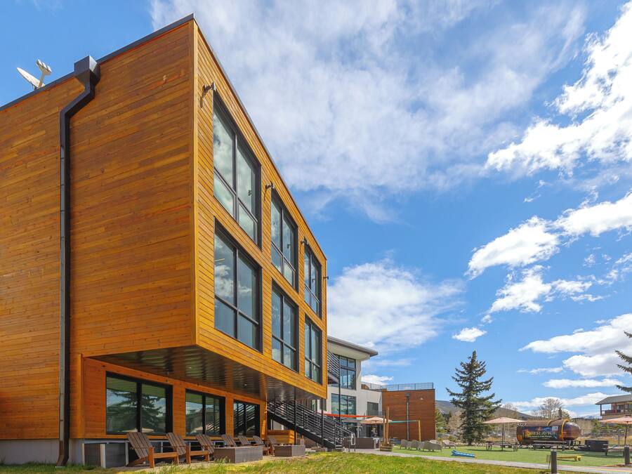 A modern building with large windows, a wooden facade, and a staircase leading to a second floor.