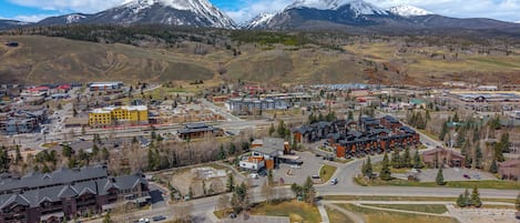A town with a mix of modern and traditional buildings, a central road, and a mountainous backdrop.