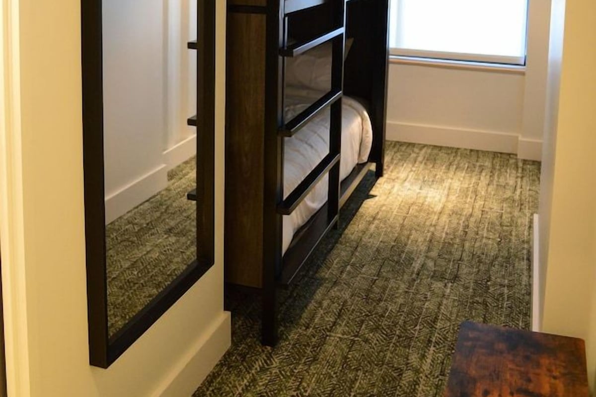 Quarto com beliche, janela com luz natural e ar-condicionado aparente.