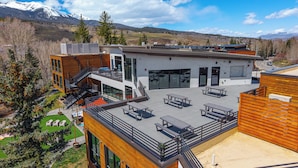Un bâtiment moderne doté d’un patio sur le toit, de grandes fenêtres et offrant une vue sur les montagnes.