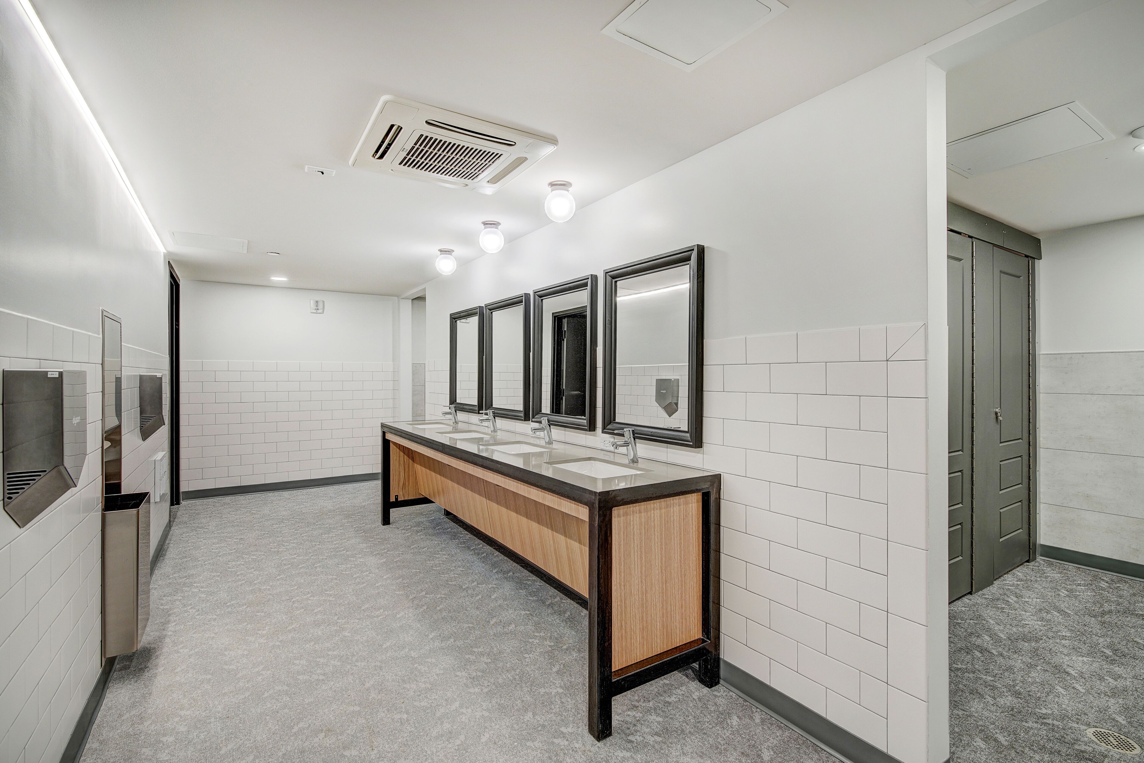 A modern bathroom with three sinks, a mirror, and a ventilation system.