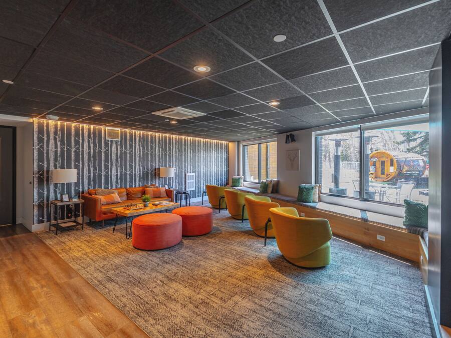Un espacio lounge moderno con sofá, otomanas y una mesita de centro.