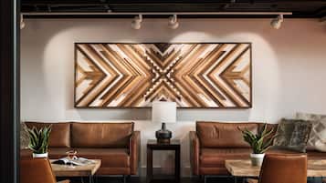 A modern lounge area with leather sofas, a wooden coffee table, and a large geometric wall art piece.