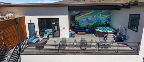 A modern building with a rooftop patio, outdoor seating, a hot tub, and a mural.