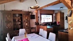 A dining area with a wooden table, chairs, and a bright window. - jlulbert's chalet near biotop lake and center (Combloux)