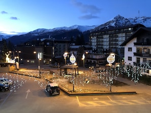 A parking area with cars, illuminated signs, and buildings with balconies in the background. - Studio (Sauze d'Oulx)