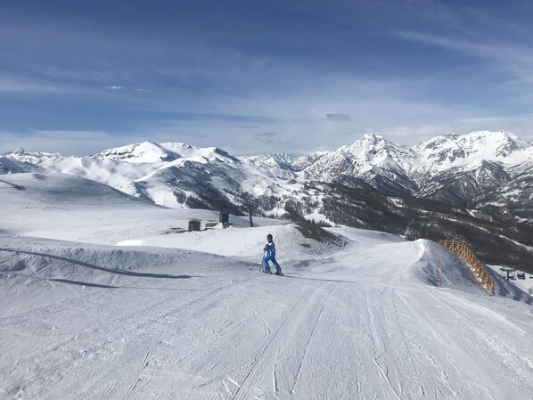 A snowy ski slope with a skier in blue attire. - Studio (Sauze d'Oulx)