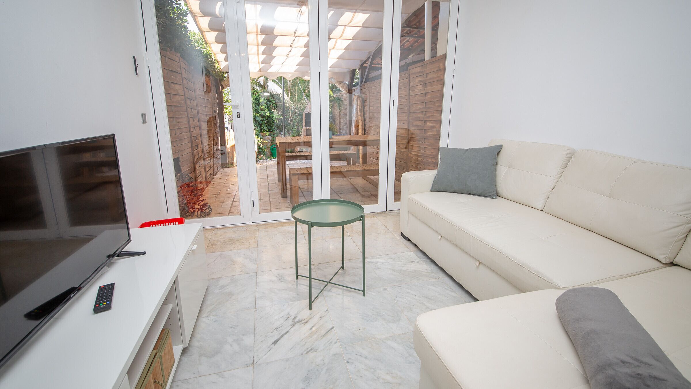 A modern living room with a flat-screen TV, a sofa, and a glass-top coffee table.