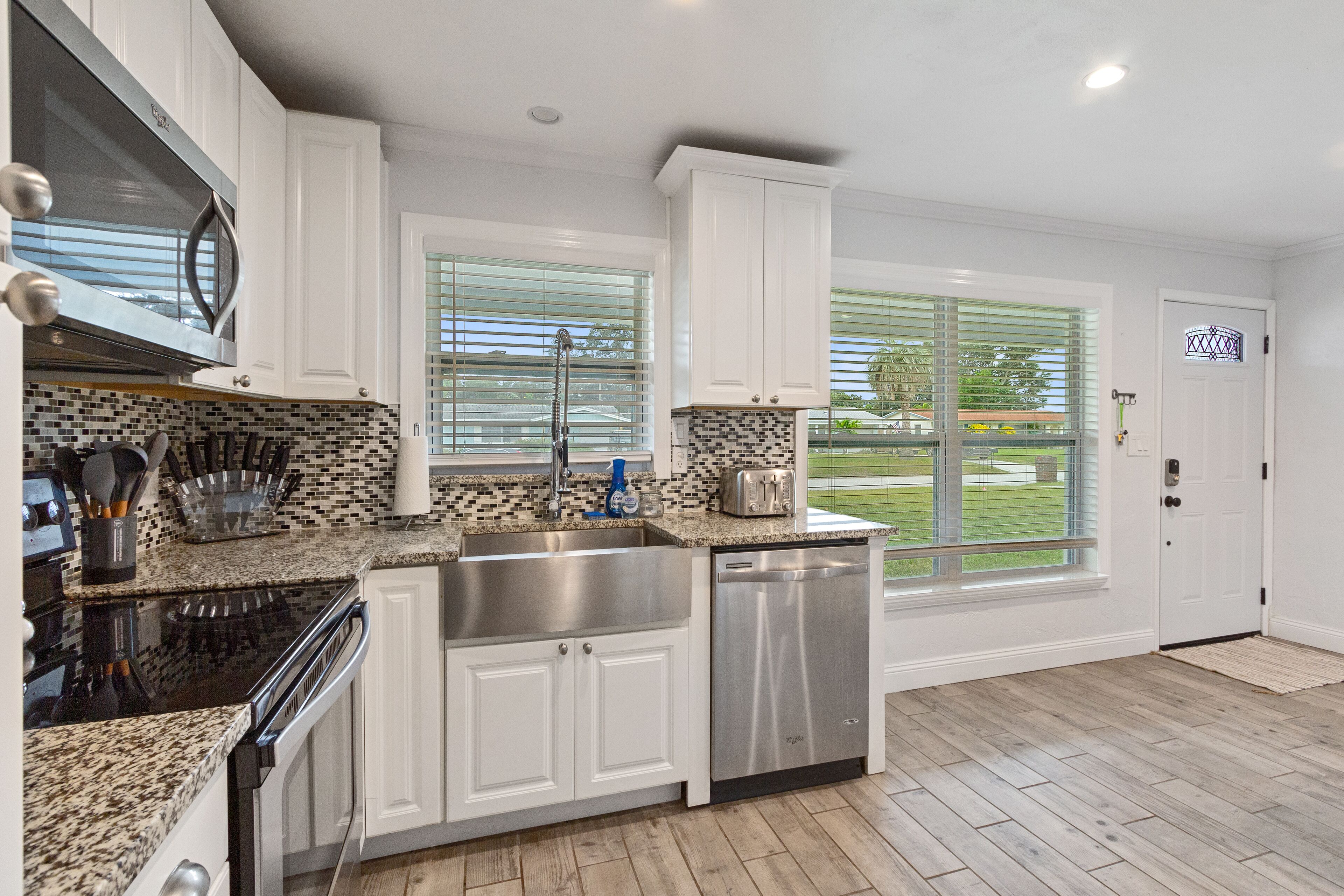 A modern kitchen with white cabinets, a stainless steel sink, and a dishwasher.