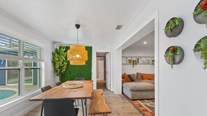 Zona menjador moderna amb taula de fusta, cadires negres i una panxa. Es veu una paret verda amb un llum penjant.