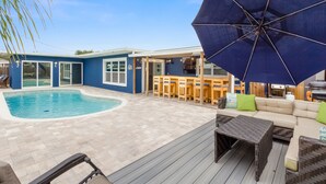 Un pati amb piscina, terrassa de fusta, mobiliari d'exterior i zona de barbacoa.