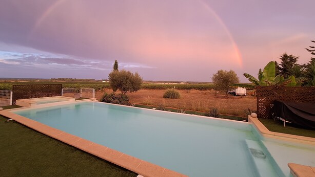Una piscina amb vistes a un vignoble i un arc de tisora al cel.