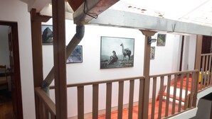 A staircase with a wooden railing, a red carpeted floor, and several framed pictures on the wall. - Pirwa B&B Cusco (Cusco)