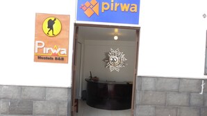 A hotel entrance with a reception desk and a decorative wall piece. - Pirwa B&B Cusco (Cusco)