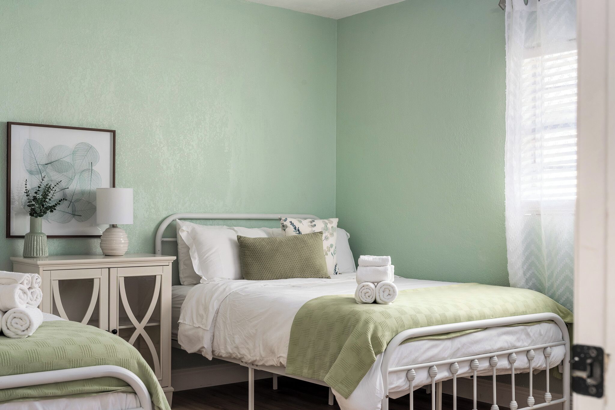 A bedroom with a bed, bedside table, and a framed botanical print.