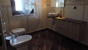 Une salle de bain équipée de toilettes, d’un bidet, d’un lavabo et d’un miroir.