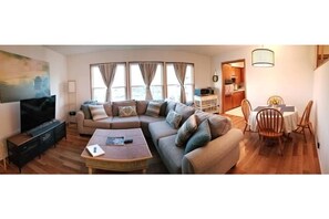 Relax in this stylish living room with a sofa, flat-screen TV, and dining area.