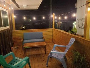 Relax in this serene outdoor seating area with a bench and chairs, offering a view of the night sky.