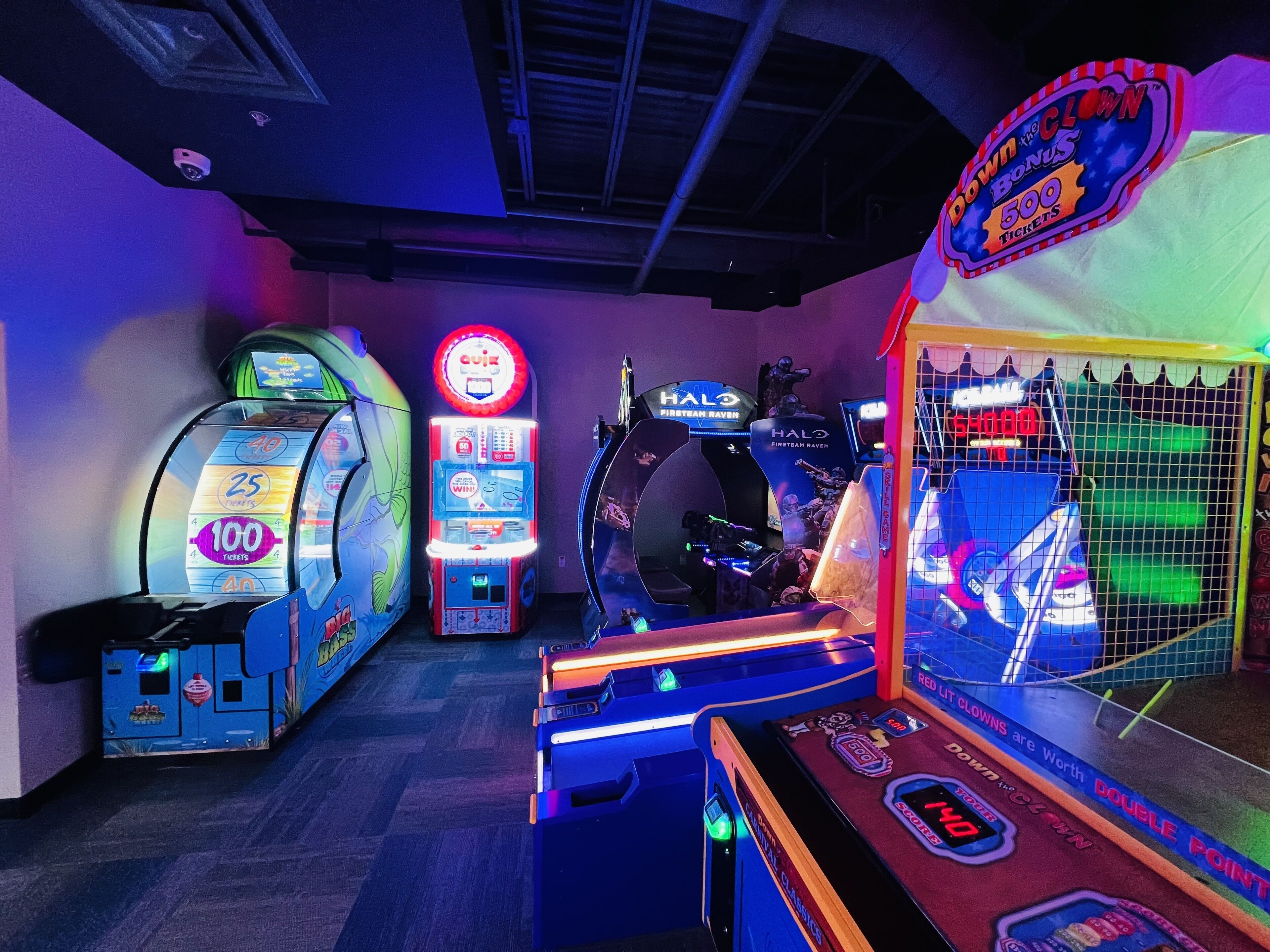 A gaming arcade with various machines, including a claw machine and a quiz machine.