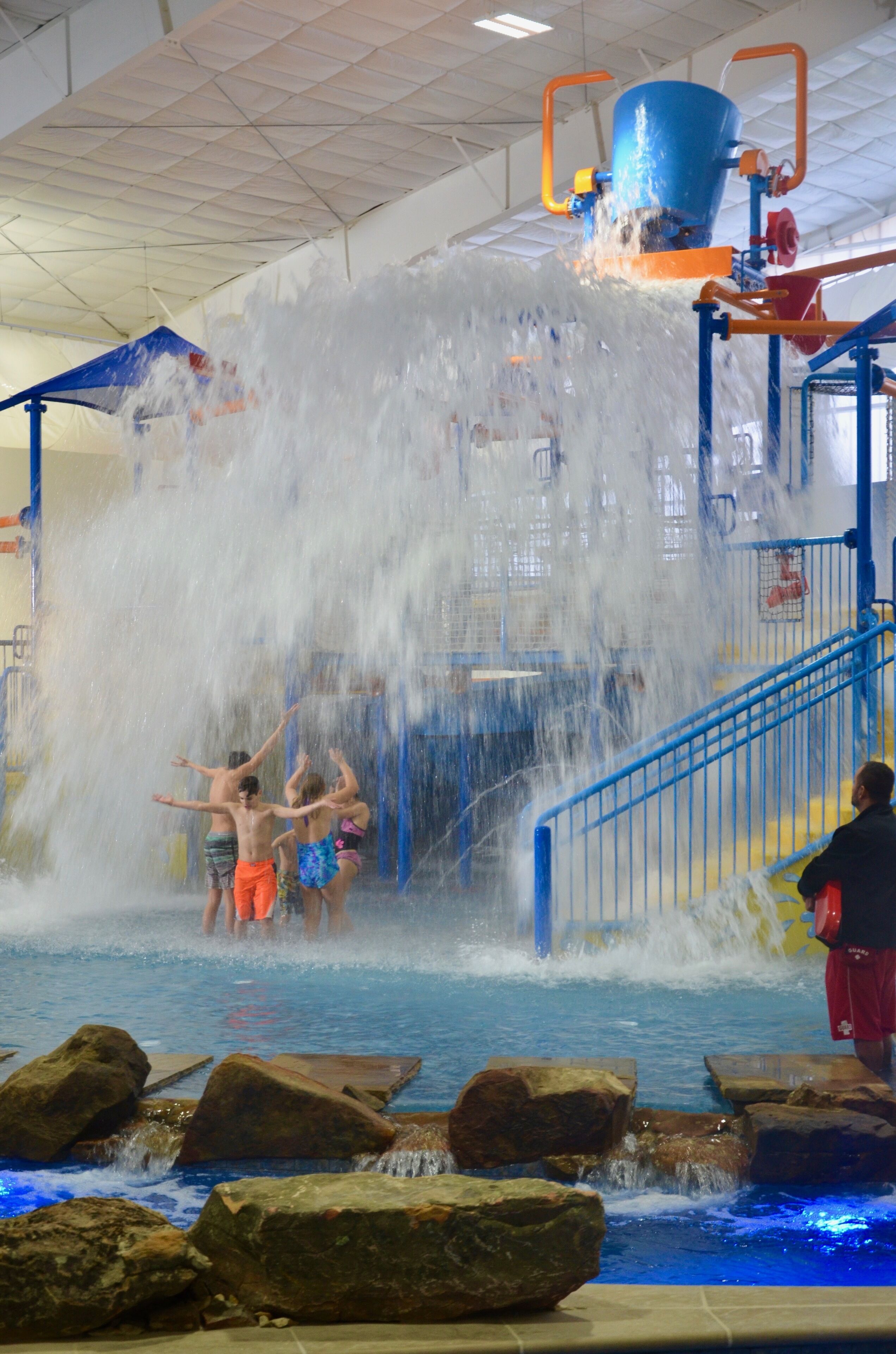 Een speelgedeelte met water, inclusief verschillende waterstralen en een zwembad.