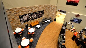 A restaurant with a stone wall, a mural, orange chairs, and tables. - 7Clans Hotel & Resort (Newkirk)