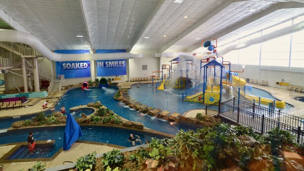 An indoor water park with multiple pools, slides, and play structures. - 7Clans Hotel & Resort (Newkirk)