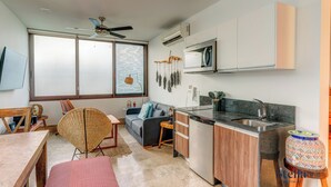 Una cocina moderna con lavavajillas incorporado, microondas y pileta. Hay un comedor con mesa y sillas de madera.