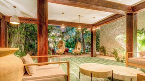Un amplio espacio interior con piscina, muebles de madera y un mural tropical.