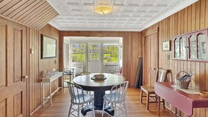Une pièce aux murs lambrés, avec une table de salle à manger ronde, des chaises et un banc.