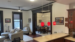 A spacious living room with a sofa, a dining area with a table and chairs, and a kitchen with a countertop and cabinets. - Condo directly on Broadway!  Location, location, location!!  Walk to everything! (Saratoga Springs)