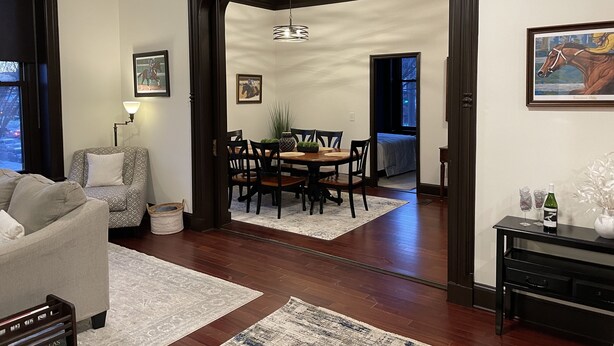 A dining area with a wooden table and chairs, a rug, and a painting on the wall. - Condo directly on Broadway!  Location, location, location!!  Walk to everything! (Saratoga Springs)