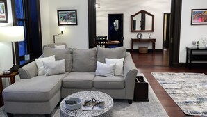 A living room with a grey sectional sofa, a round coffee table, and a patterned rug. - Condo directly on Broadway!  Location, location, location!!  Walk to everything! (Saratoga Springs)