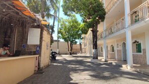 A narrow street with buildings on both sides, trees, and a motorcycle parked on the left.