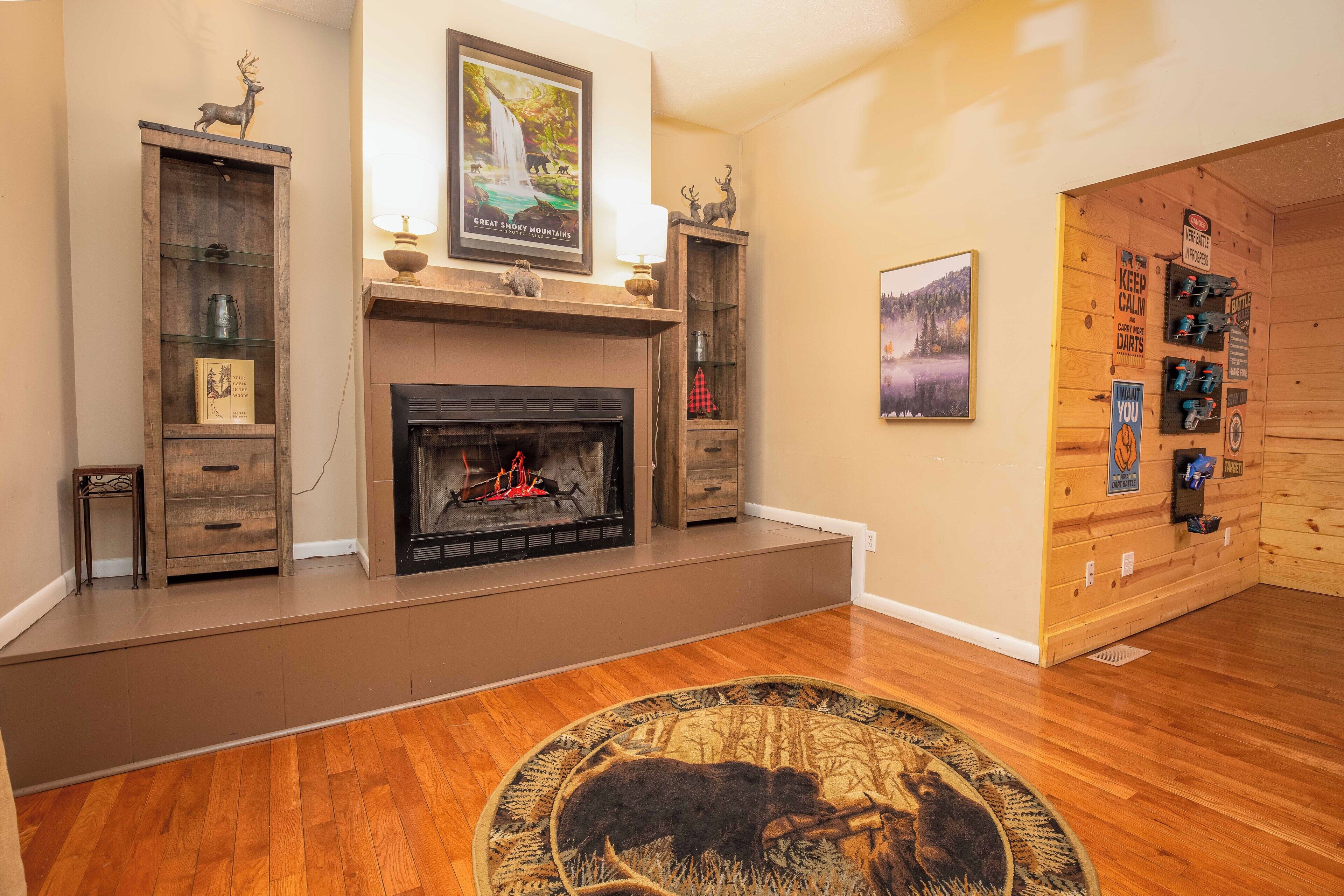 A living room with a fireplace, wooden shelves, and a rug with a moose design.