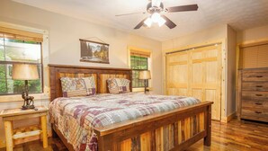 A bedroom with a large wooden bed, two bedside tables, a ceiling fan, and a wardrobe.