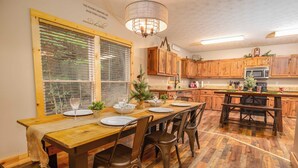 A dining area with a wooden table set for four, surrounded by wooden chairs.
