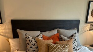 A neatly made bed with a variety of patterned pillows and a dark headboard. - City centre Apartment/Energy Corridor (Houston)