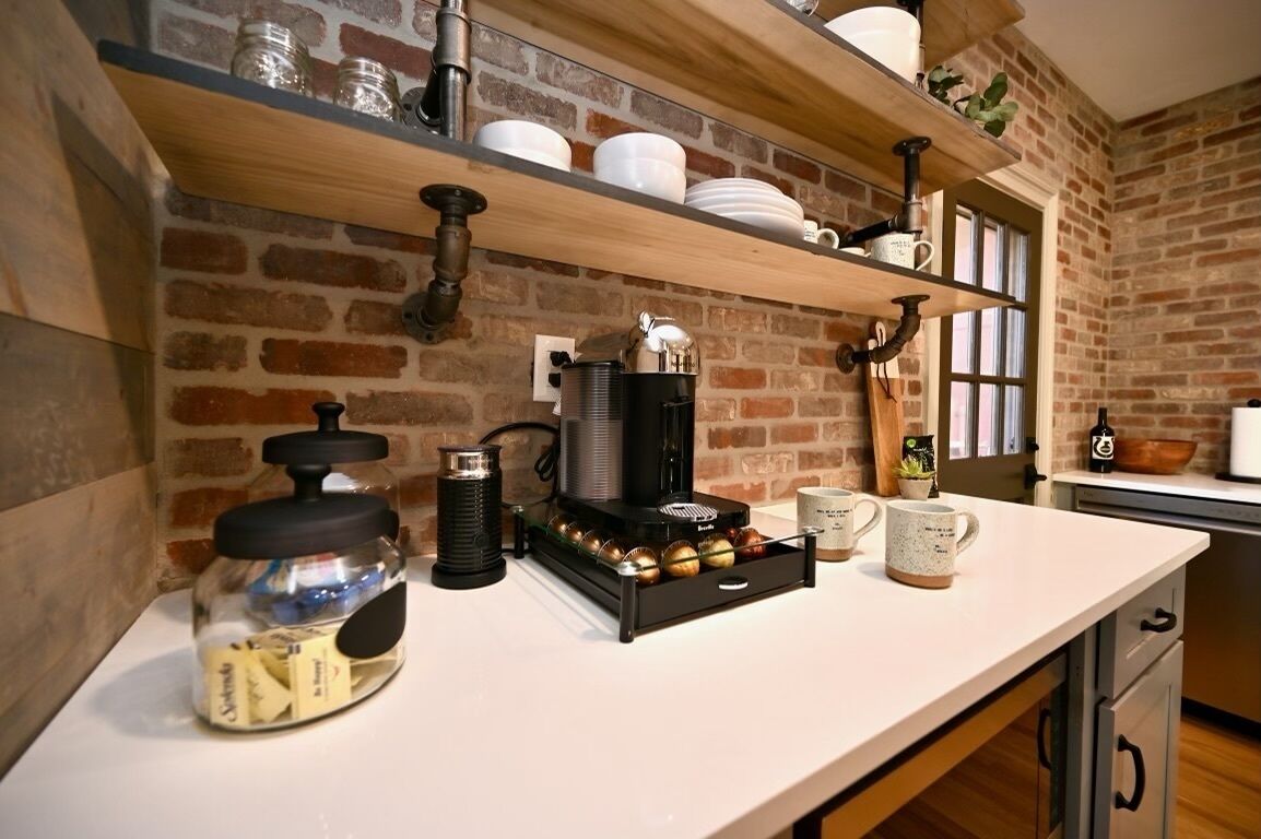 A kitchen with a coffee machine, jars, and shelves with dishes.